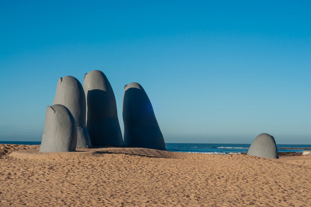 Iconic hand sculpture on sandy beach in Punta del Este, Uruguay with clear blue sky.
